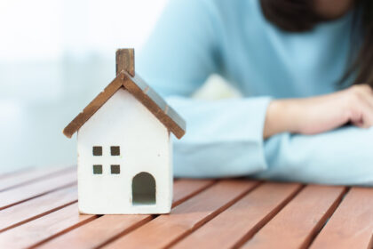 家の模型を悩みながら見つめる女性